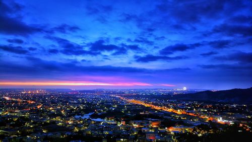 High angle view of illuminated cityscape against sky at dusk