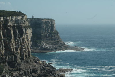 Scenic view of sea by cliff against clear sky