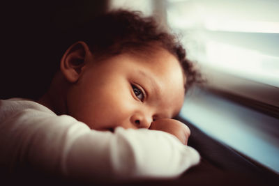 Close-up of boy sitting window at home