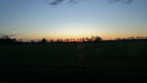 Scenic view of field against clear sky during sunset