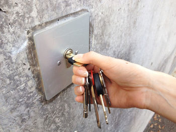 Close-up of hand holding metal against wall