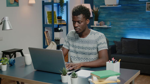 Portrait of young woman using laptop at table