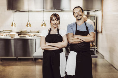 Porträtt av glatt par med armarna i kors i restaurangkök