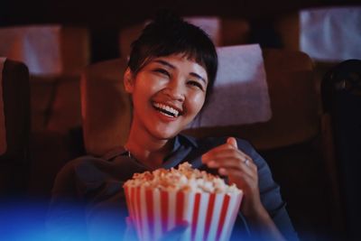 Portrait of smiling woman having popcorn at theater