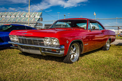 Vintage car parked on grass against blue sky