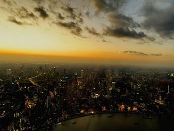 Illuminated buildings in city against sky during sunset