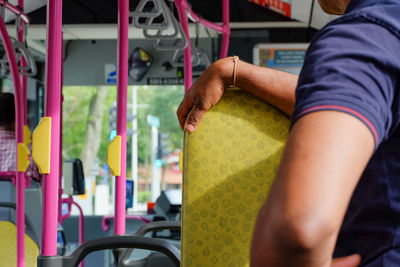 Midsection of man standing by seat in bus