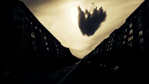 Empty road in city against cloudy sky