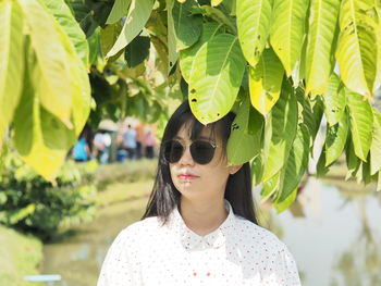 Portrait of young woman with sunglasses on leaves