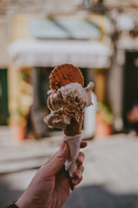 Cropped hand holding ice cream cone in city