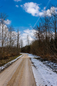 Road amidst bare trees against sky during winter