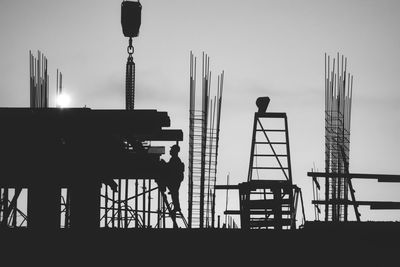 Low angle view of silhouette cranes against sky