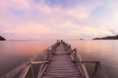 Pier over sea against sky during sunset