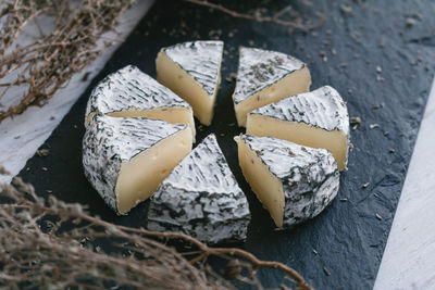 High angle view of cheese slices and herbs on cutting board in kitchen