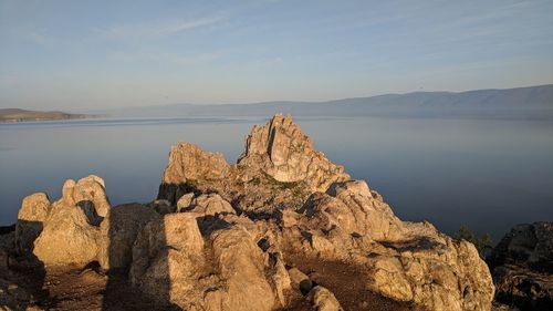 Rock formations by sea against sky