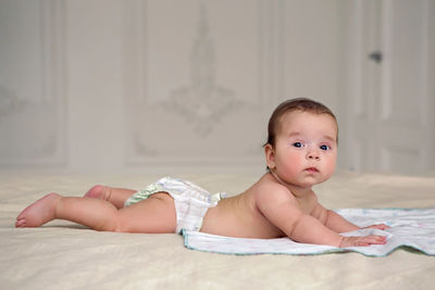 Portrait of cute baby boy lying on bed at home