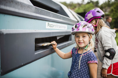 Girl putting rubbish into recycling bin