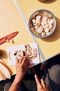 Man preparing healthy breakfast with fruits and oat flakes outdoors on camping