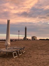 Built structure on beach against sky during sunset