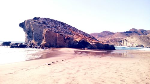 Rock formation at beach against clear sky