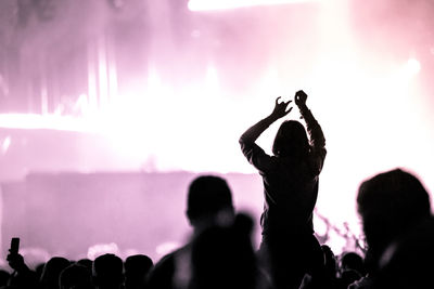 Crowd with arms outstretched at concert. summer music festival concept. purple stage lights