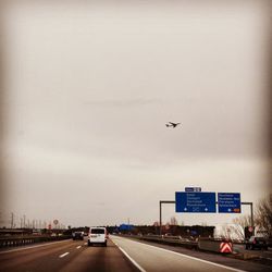 Road sign in city against sky