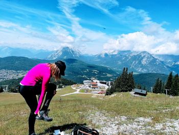 Hiker changing her shoes on mountain against sky