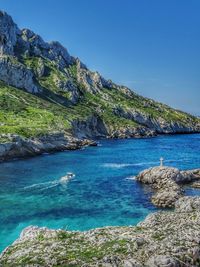 Scenic view of sea and mountains against blue sky