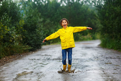 Boy jumping through muddy puddles in the rain