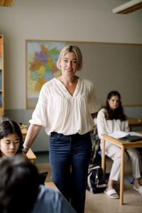 Portrait of female teacher standing in high school classroom