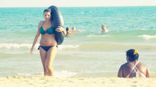 Rear view of friends standing on beach against sky