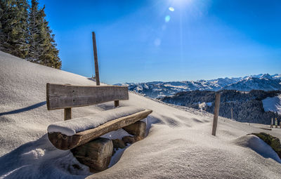 Snow covered landscape against blue sky