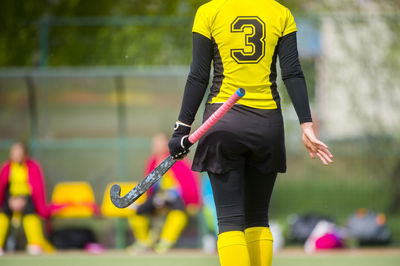 Rear view of woman holding hockey stick