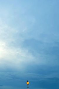 Low angle view of illuminated lamp post against cloudy sky