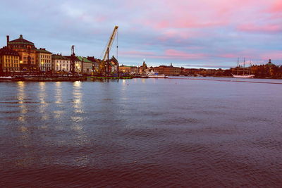 Scenic view of sea by buildings against sky at sunset