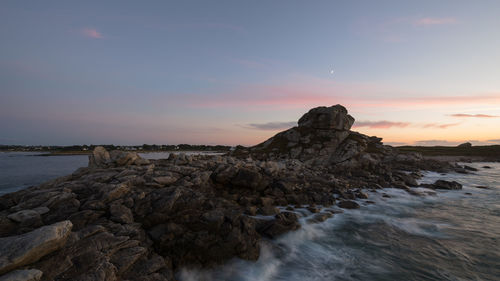 Rock formation on sea against sky during sunset