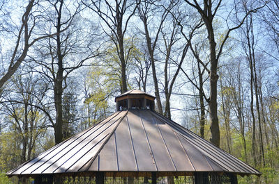 Built structure by bare trees in park against sky