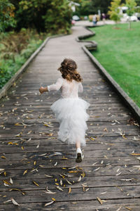 Rear view of girl running on boardwalk