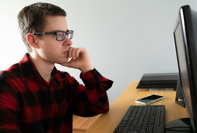 Young man using mobile phone while sitting on table