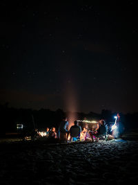 People at beach against sky at night