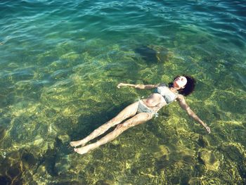 High angle view of woman relaxing in sea on sunny day