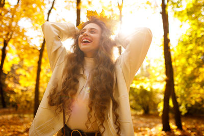 Portrait of young woman standing against trees