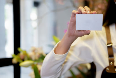 Midsection of woman holding blank business card