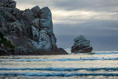 Rock formations on sea shore against sky