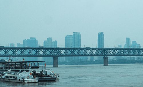 Bridge over river in city against clear sky