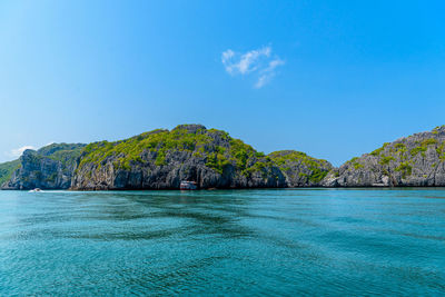 Scenic view of sea and rocks against blue sky