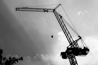 Low angle view of cranes at construction site against sky