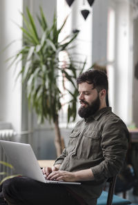 Young man using laptop while sitting on chair