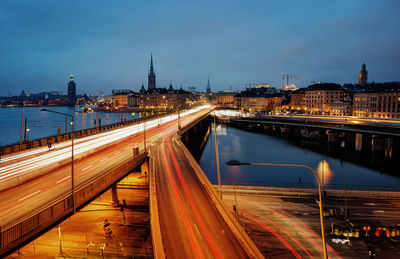 Light trails on bridge in city against sky