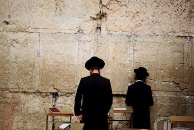 Rear view of people standing against wall